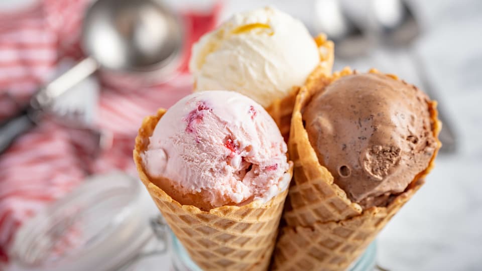 Three ice cream cones, pink, white and brown.